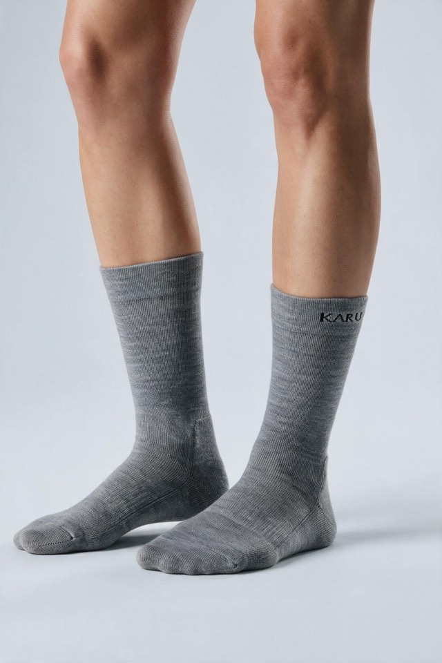 Tjäktja Sock pair in ash, worn on the feet, studio product shot on a seamless neutral ground